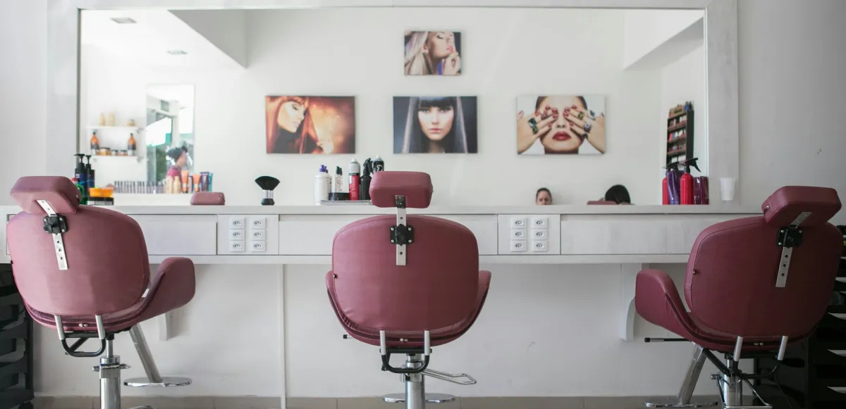 Interior de peluquería con sillones frente a grandes espejos