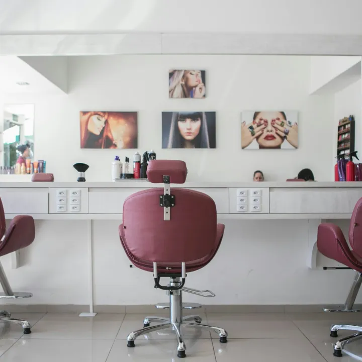 Interior de peluquería con sillones frente a grandes espejos